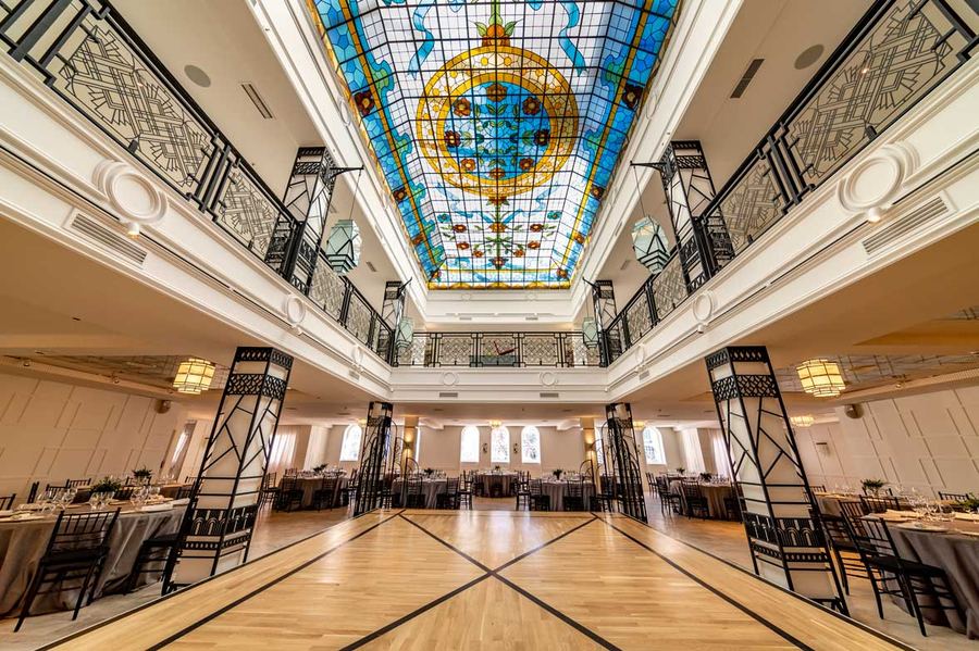 Salón con techo de vidriera y mesas montadas para un banquete