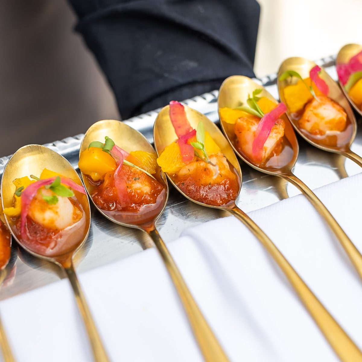 Cucharas doradas con bocados de cóctel servidas en un evento de empresa