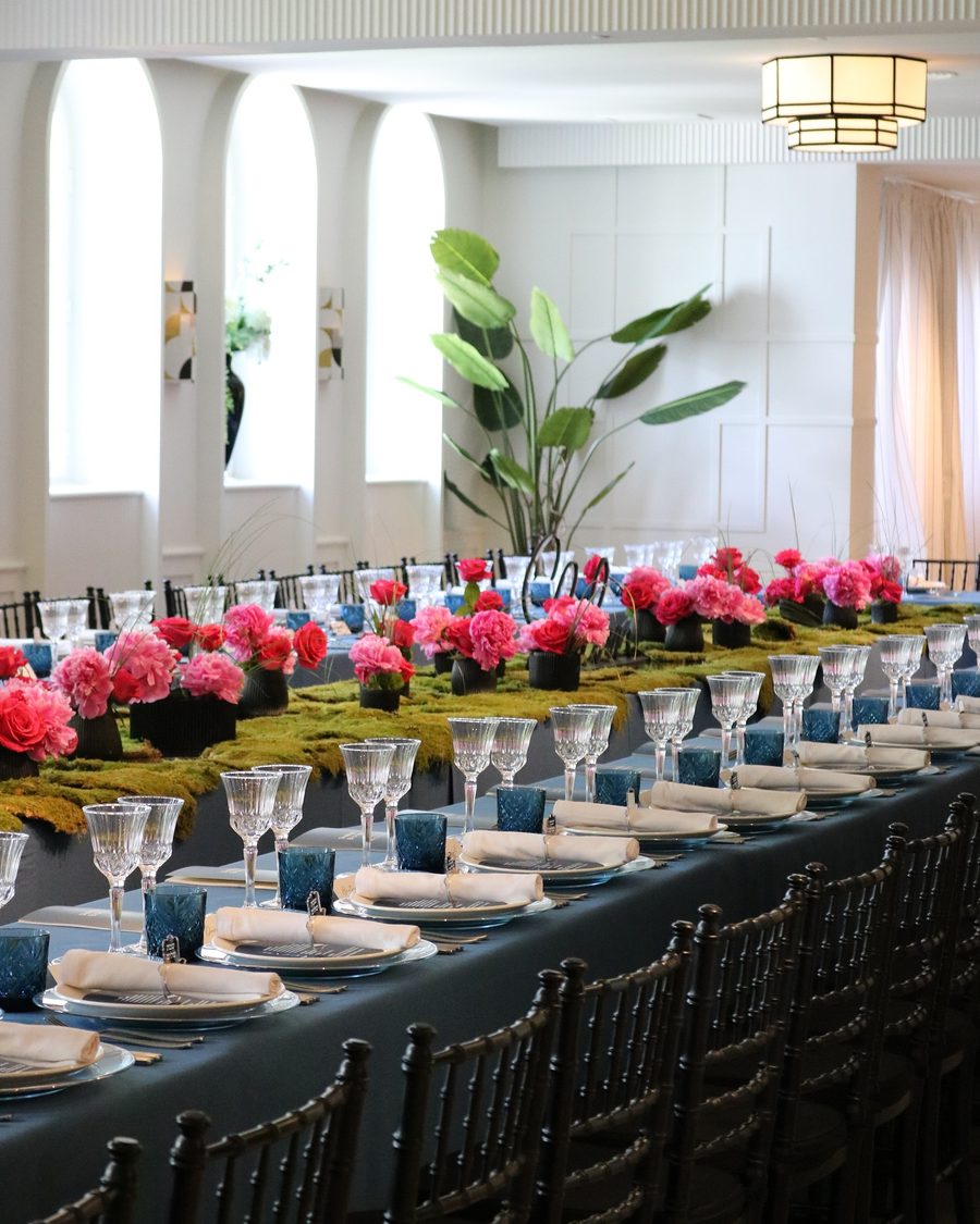 Mesa larga con flores rosas en el salón de arcos